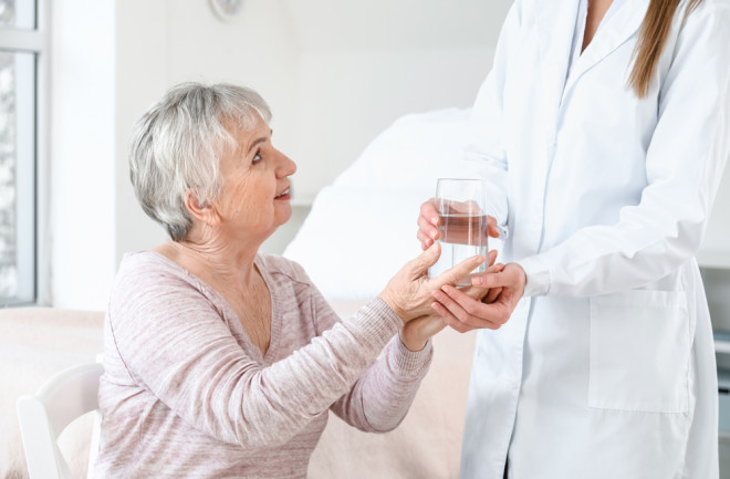 eoder woman in light pink shirt getting water from nurse memory care