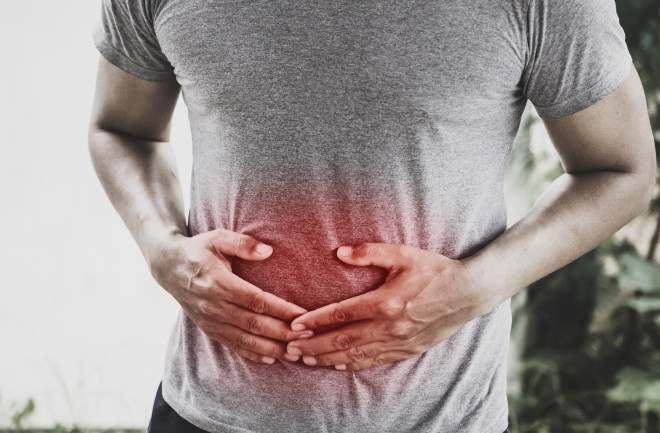 Man standing and holding stomach with both hands from pain 