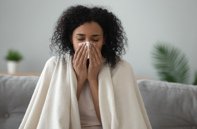 Woman blowing her nose showing a common cold symptom of HMPV 