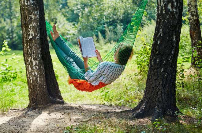 woman in hammock reading a book - shutterstock 147277643