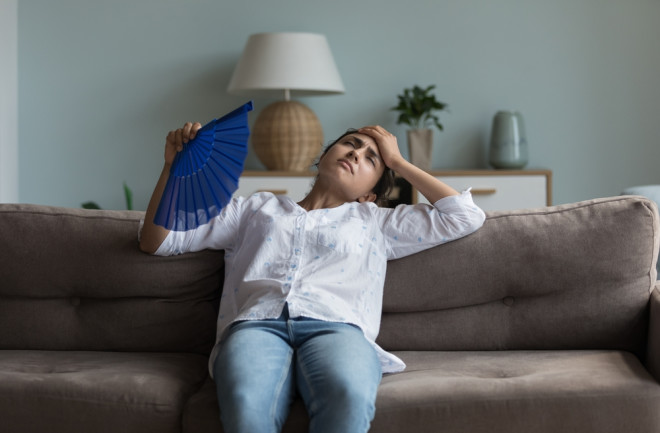 Overheated woman fanning herself on the couch 