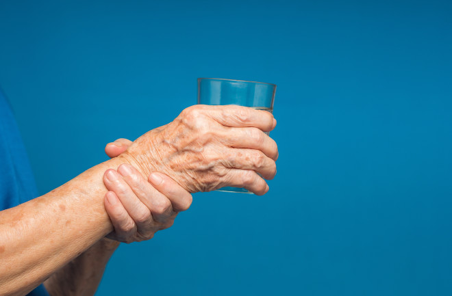 Person struggling to hold a glass showing Parkinson's disease symptoms