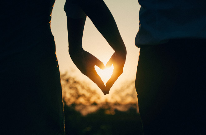 Silhouette of couple holding hands in a heart shape 