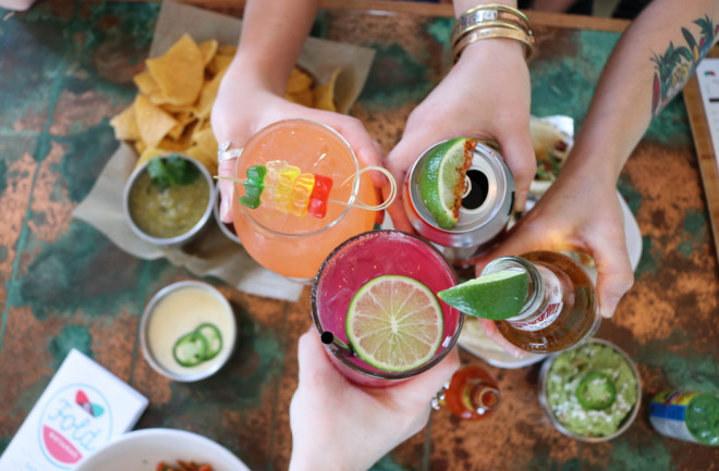 Four hands cheersing four different alcoholic beverages - Shutterstock