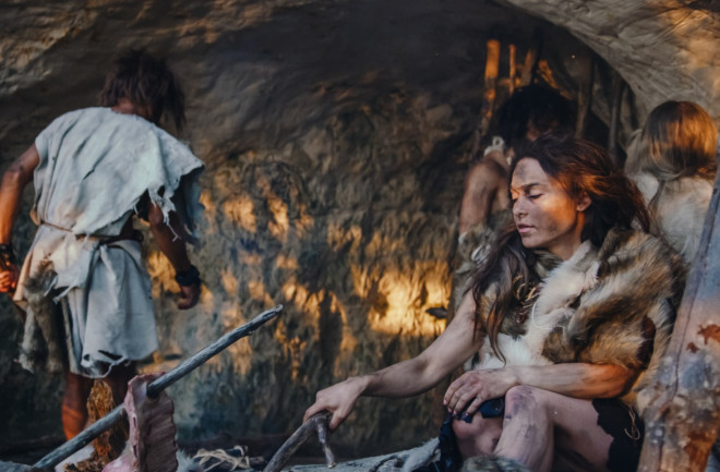 Tribe-of-Hunter-Gatherers-Wearing-Animal-Skin- in-a-Cave-cooking-meat-over-fire